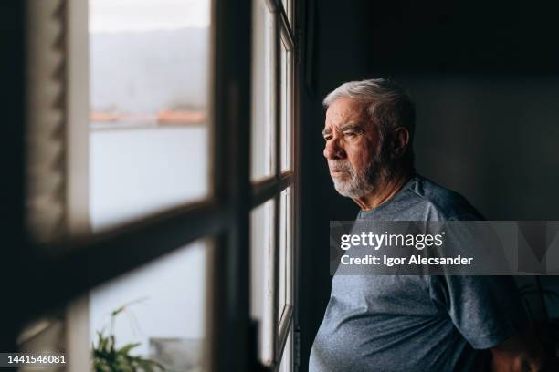 elderly man looking out the window - alleen één seniore man stockfoto's en -beelden