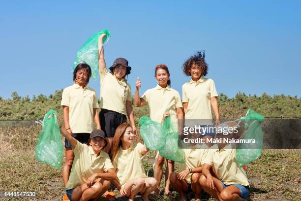 fellow women doing beach cleaning. - altruism stock-fotos und bilder