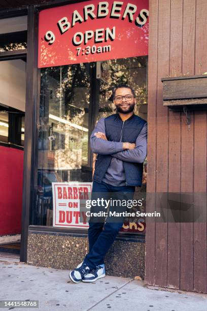 black customers receive a haircut from barbers at a black owned barbershop - african american hair salon stock pictures, royalty-free photos & images