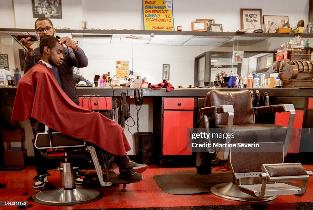Schwarze Kunden erhalten einen Haarschnitt von Friseuren in einem Black-eigenen Friseursalon