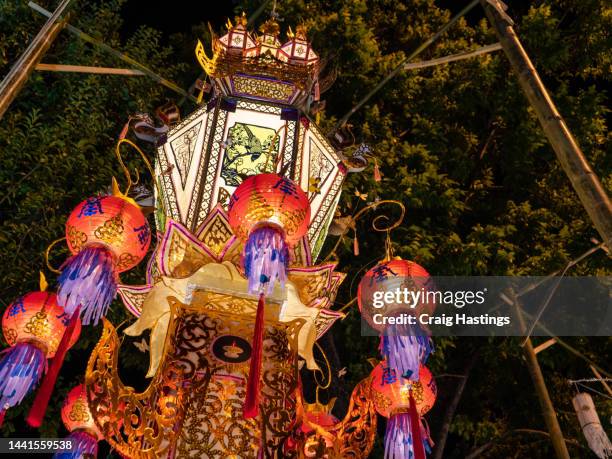 bangkok loi krathong thai chinese style lanterns of many colours on display in temple. colourful illuminations for ancient style lamps shine across the street. establishing shot of south east asia tourist area with arts and crafts - buddha's birthday stock-fotos und bilder