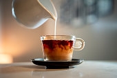 Close-up shot of a poring milk in a hot tea.