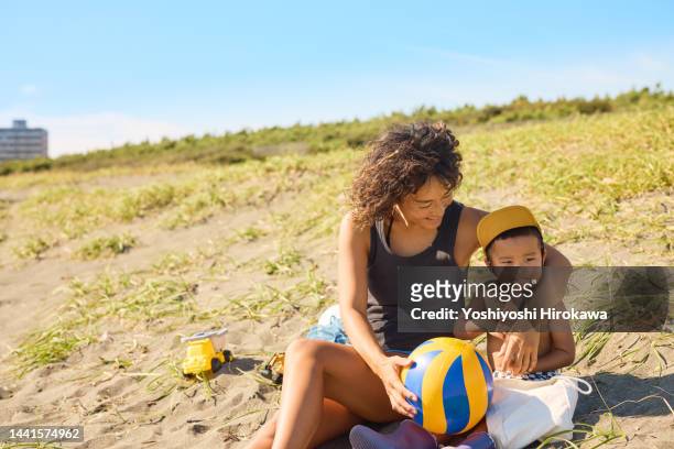 mother and child sitting on the beach - shizuoka prefecture stock pictures, royalty-free photos & images