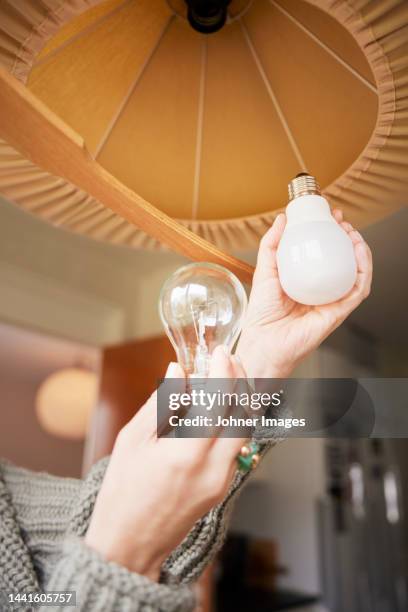 woman's hands changing light bulb - lampje-vervangen stockfoto's en -beelden