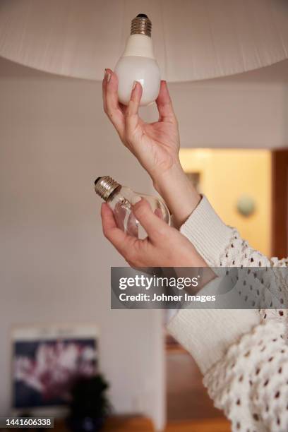 woman's hands changing light bulb - lampje-vervangen stockfoto's en -beelden