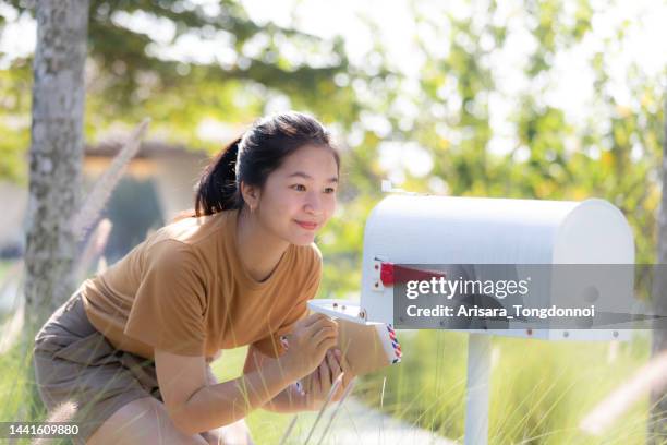 woman looking at letter in mailbox - checking letterbox stock pictures, royalty-free photos & images