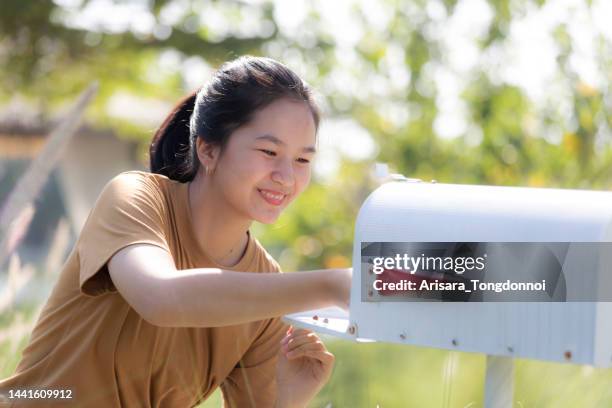 woman looking at letter in mailbox - openbare brievenbus stockfoto's en -beelden
