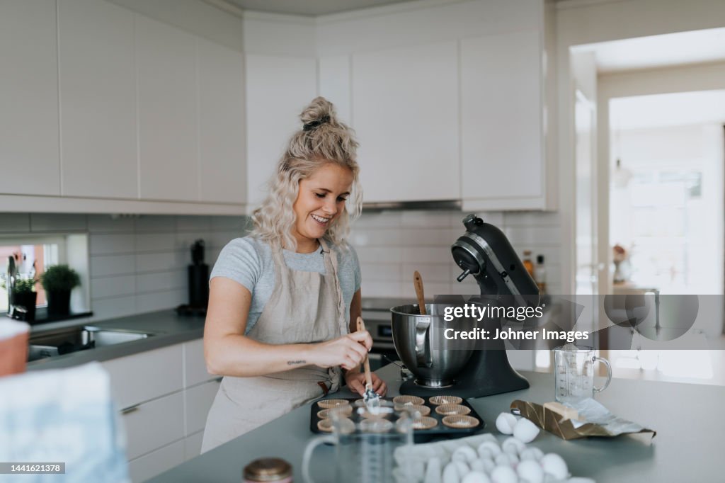 Woman in kitchen preparing cupcakes