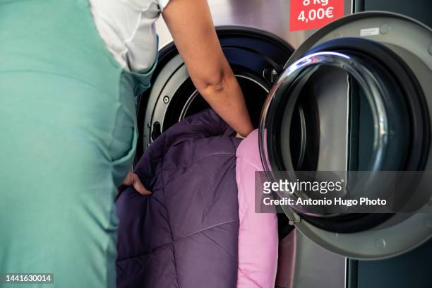 pregnant woman in a laundry. putting the clothes to be washed in the washing machine. - money laundery stock pictures, royalty-free photos & images