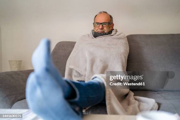 senior man wrapped in blanket sitting on sofa at home - shaking bildbanksfoton och bilder