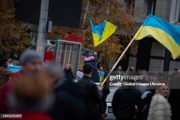 Woman with Ukrainian flag sitting on atop a car during the celebration of the city's liberation on November 12, 2022 in Kherson, Ukraine. Kherson,...