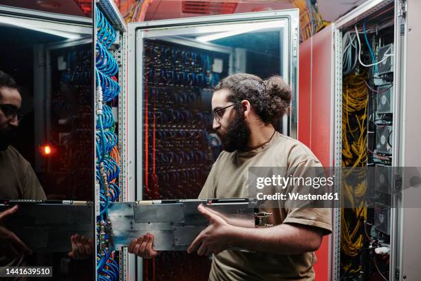 technician inserting machine part in server at data center - inserting stock-fotos und bilder