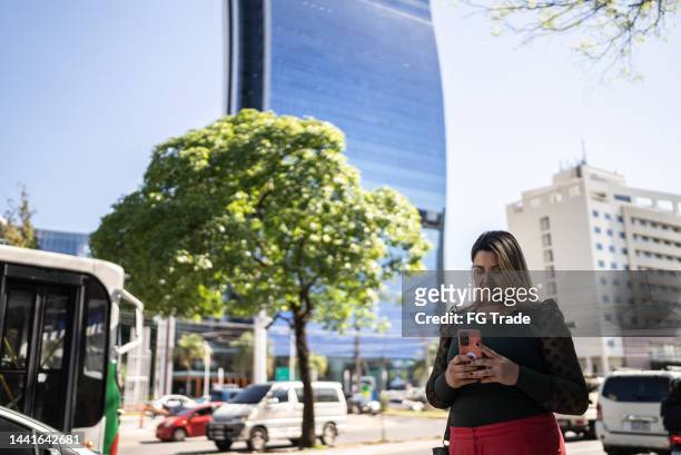 mid adult woman walking in the city while using mobile phone - asuncion paraguay stock pictures, royalty-free photos & images