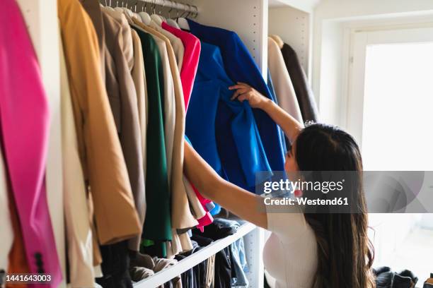 woman choosing clothes in closet - kast stockfoto's en -beelden
