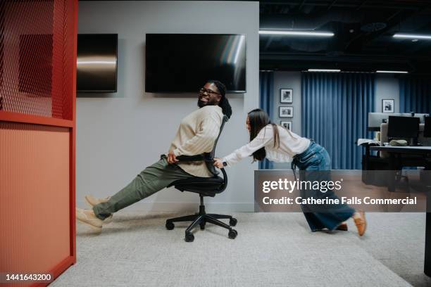 comical image of the late night antics of two misbehaving office workers - man wheel chair stock pictures, royalty-free photos & images