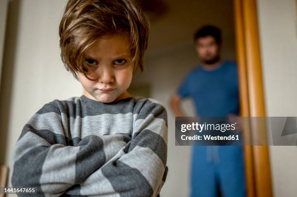 father looking at angry son at home - straffen stockfoto's en -beelden