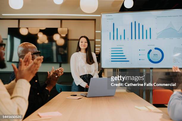 a young woman finishes a presentation and she receives a round of applause from impressed colleagues. - enterprise stock pictures, royalty-free photos & images