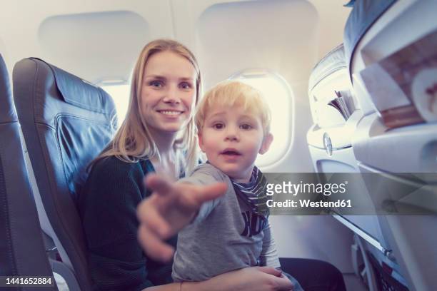 mother with son in airplane - greif stock-fotos und bilder