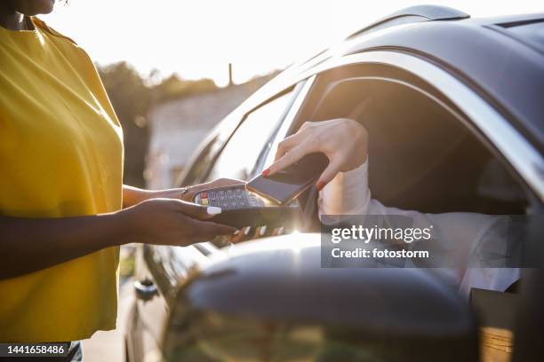 cut out shot of unrecognizable customer paying with smart phone at the curbside pickup through the car window - park service stock pictures, royalty-free photos & images