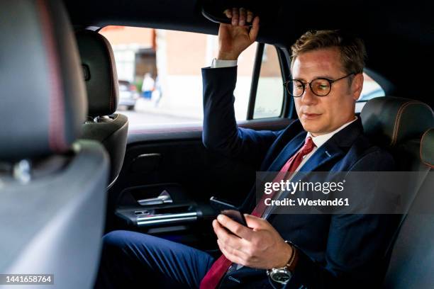 businessman using smart phone sitting in car - management car smartphone stock pictures, royalty-free photos & images
