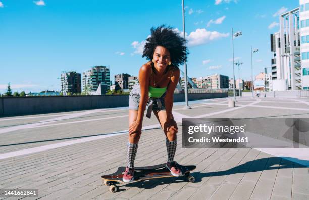 happy young woman standing on skateboard in city - woman longboard stock-fotos und bilder