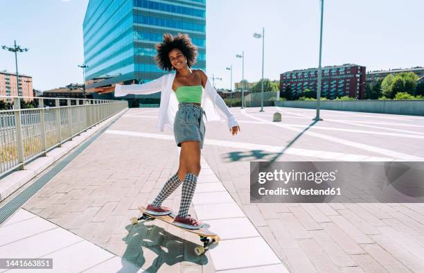 carefree woman having fun longboarding on footpath - woman longboard stock-fotos und bilder