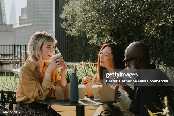 a group of coworkers enjoy an alfresco lunch - enjoying coffee cafe morning light stock-fotos und bilder