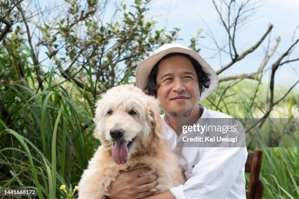 man holding a dog with a smile in the meadow. - cute dog with man stock pictures, royalty-free photos & images