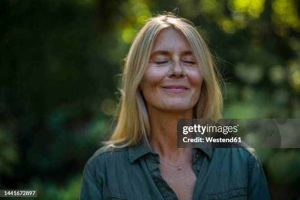 smiling mature woman with eyes closed in garden - beautiful blonde babes stock pictures, royalty-free photos & images