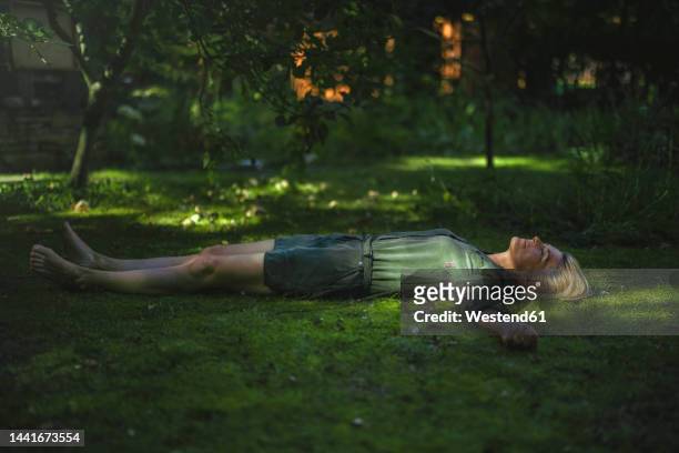woman with arms outstretched lying on grass - im gras liegen stock-fotos und bilder