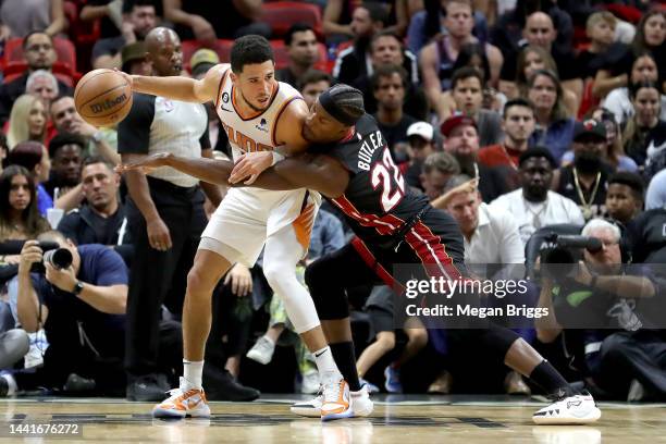 Jimmy Butler of the Miami Heat guards Devin Booker of the Phoenix Suns during the second quarter at FTX Arena on November 14, 2022 in Miami, Florida....