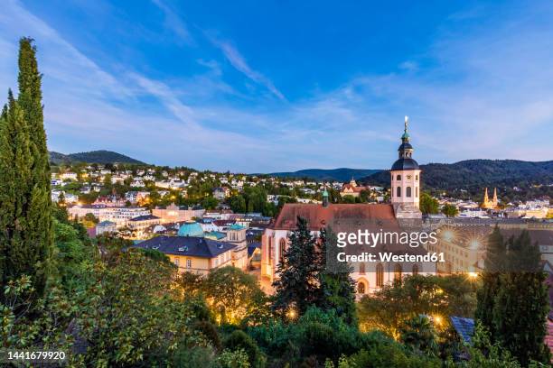 germany, baden-wurttemberg, baden-baden, town in black forest range at dusk with church in foreground - baden baden stock pictures, royalty-free photos & images