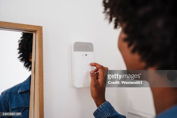 woman activating burglar alarm at home - alarm system stock pictures, royalty-free photos & images