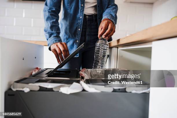 young woman recycling plastic bottles in kitchen at home - jetée photos et images de collection