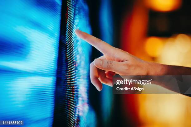 close up of woman's hand touching illuminated and multi-coloured led display screen, connecting to the future. people, lifestyle and technology - market intelligence imagens e fotografias de stock