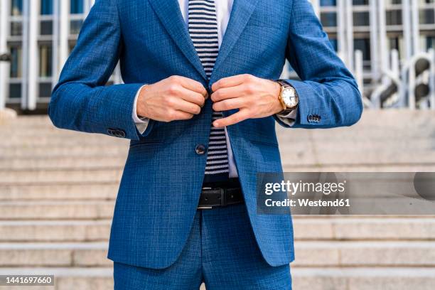 businessman buttoning suit jacket in front of staircase at office park - knäppa knappar bildbanksfoton och bilder