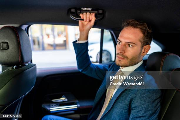 businessman holding handle sitting in taxi - manilla fotografías e imágenes de stock