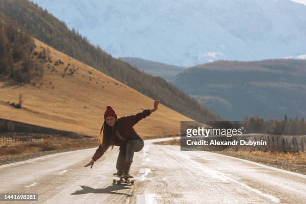 happy young woman riding a skateboard in the mountains on the road. the concept of youth culture and freedom. - longboard skating 個照片及圖片檔