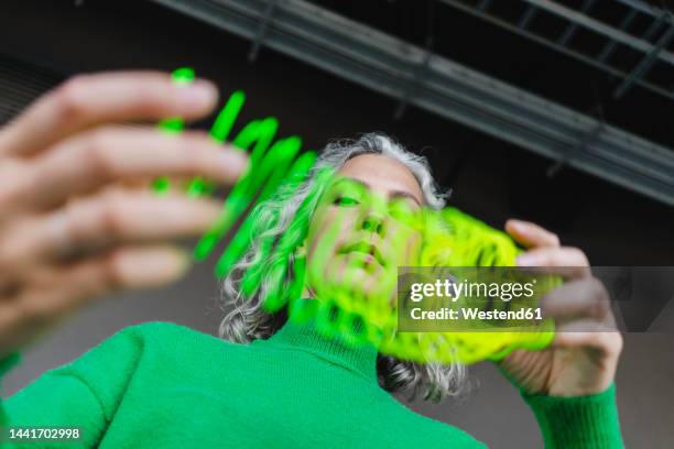 woman stretching green metal coil toy - metal coil toy stockfoto's en -beelden