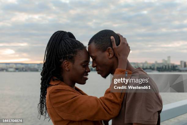 romantic couple head to head by railing in front of river - falling in love stock pictures, royalty-free photos & images