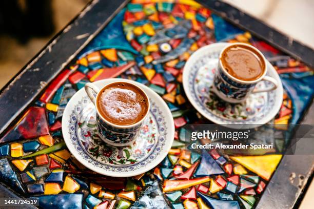 two cups of traditional turkish coffee on a multi-colored mosaic table - turkish coffee drink stock pictures, royalty-free photos & images
