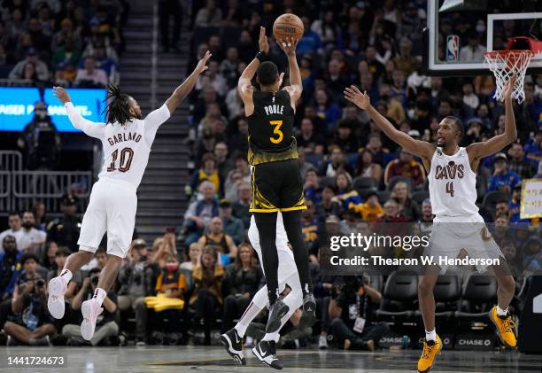 Jordan Poole of the Golden State Warriors shoots over Darius Garland and Evan Mobley of the Cleveland Cavaliers during the second quarter of an NBA...