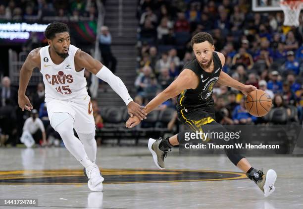 Stephen Curry of the Golden State Warriors dribbles the ball past Donovan Mitchell of the Cleveland Cavaliers in the third of an NBA basketball game...