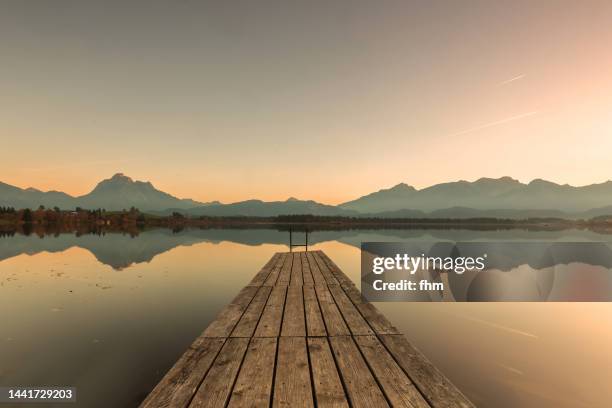 idyllic lake with jetty at sunset (lake hopfen - bavaria/ germany) - orilla del lago fotografías e imágenes de stock