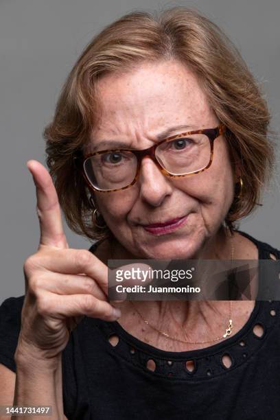 serious senior woman front mugshot scolding pointing at you - index finger stock pictures, royalty-free photos & images