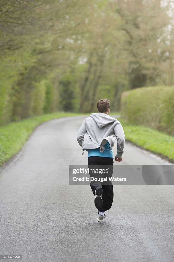 Man running along road in countryside.