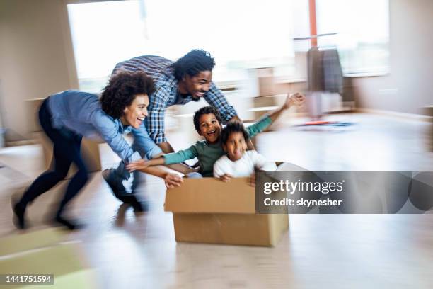 playful black family having fun while moving into new home in blurred motion. - man with moving boxes authentic stockfoto's en -beelden