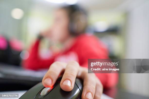 close-up of hand of a child sitting with headphones on his head manipulating the computer mouse while playing his video games on the computer at home against apartment decoration in the background - close up computer mouse bildbanksfoton och bilder