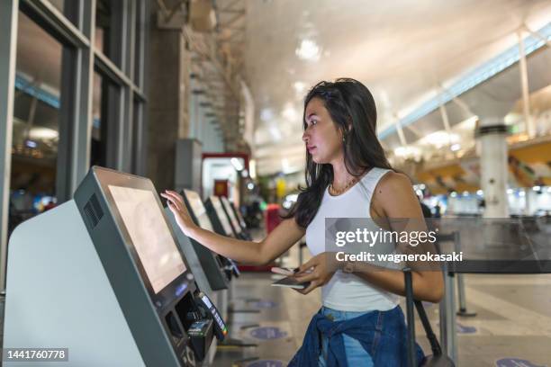 jeune femme utilisant l'enregistrement libre-service à l'aéroport - libre service photos et images de collection