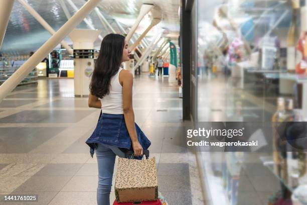 porträt einer jungen frau mit einkaufstaschen am flughafen - airport shopping stock-fotos und bilder
